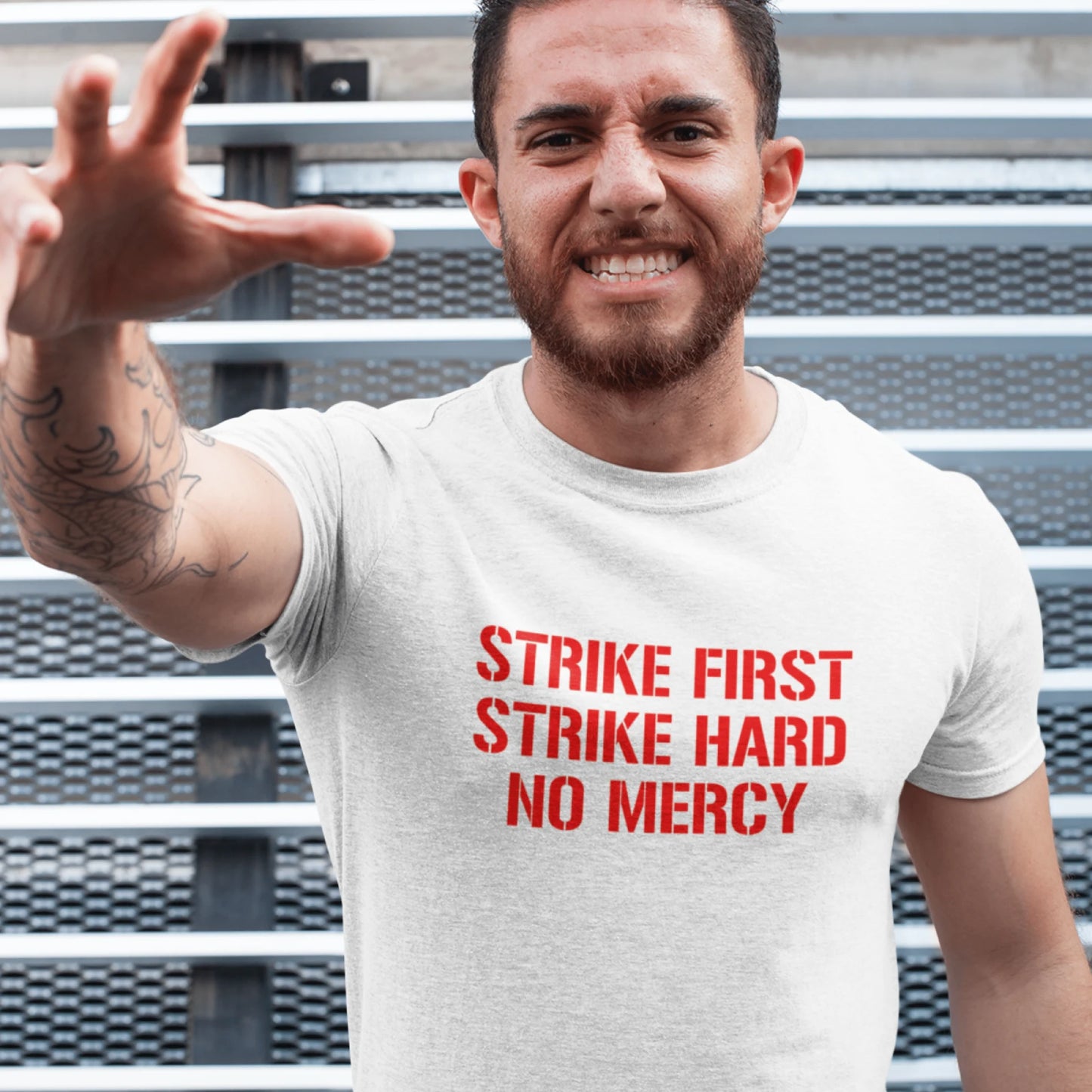 Chlap v bílém tričku s nápisem Strike First, Strike Hard, No Mercy