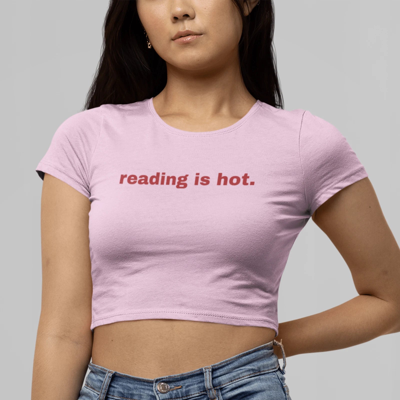 Holka v růžovým crop topu s nápisem Reading is hot.