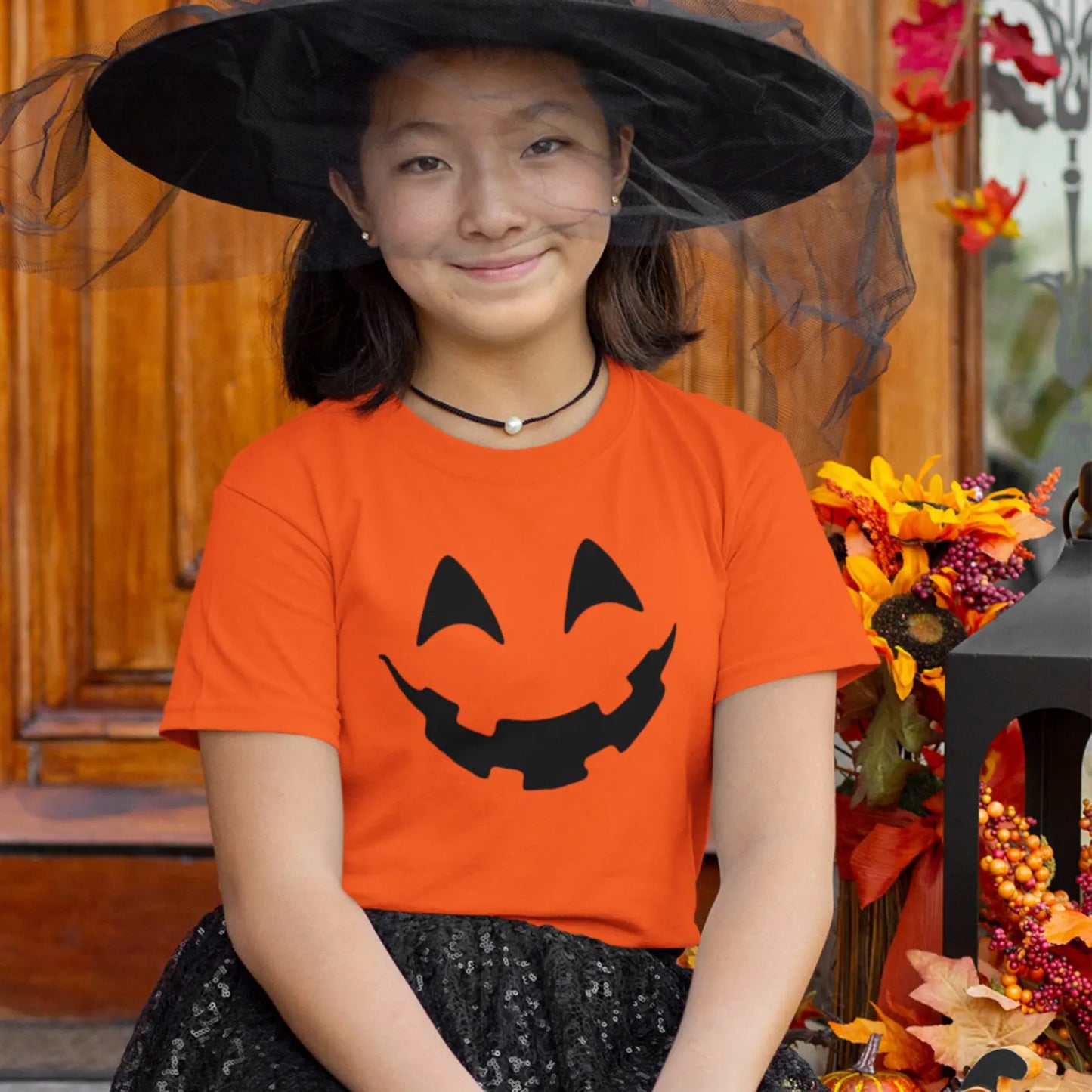 Holka v dětském oranžovém tričku na Halloween s obličejem dýně