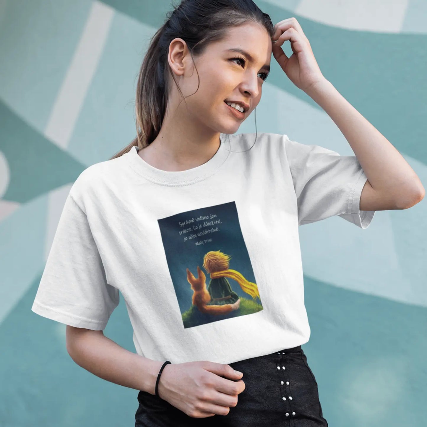 Holka v bílém tričku s fotografií Malého prince s liškou a ikonickým mottem