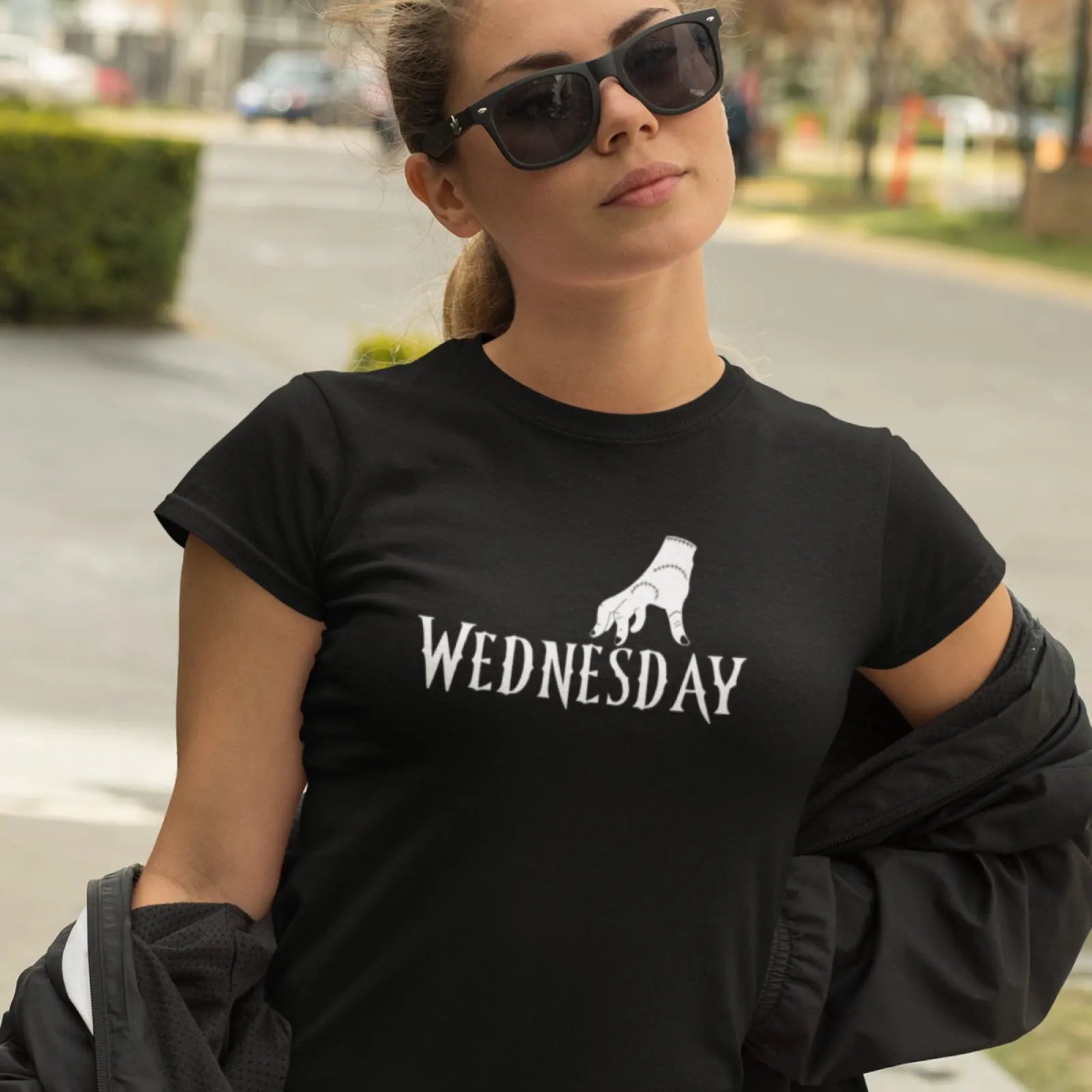 Holka v černém tričku s nápisem Wednesday a čarodějnou rukou