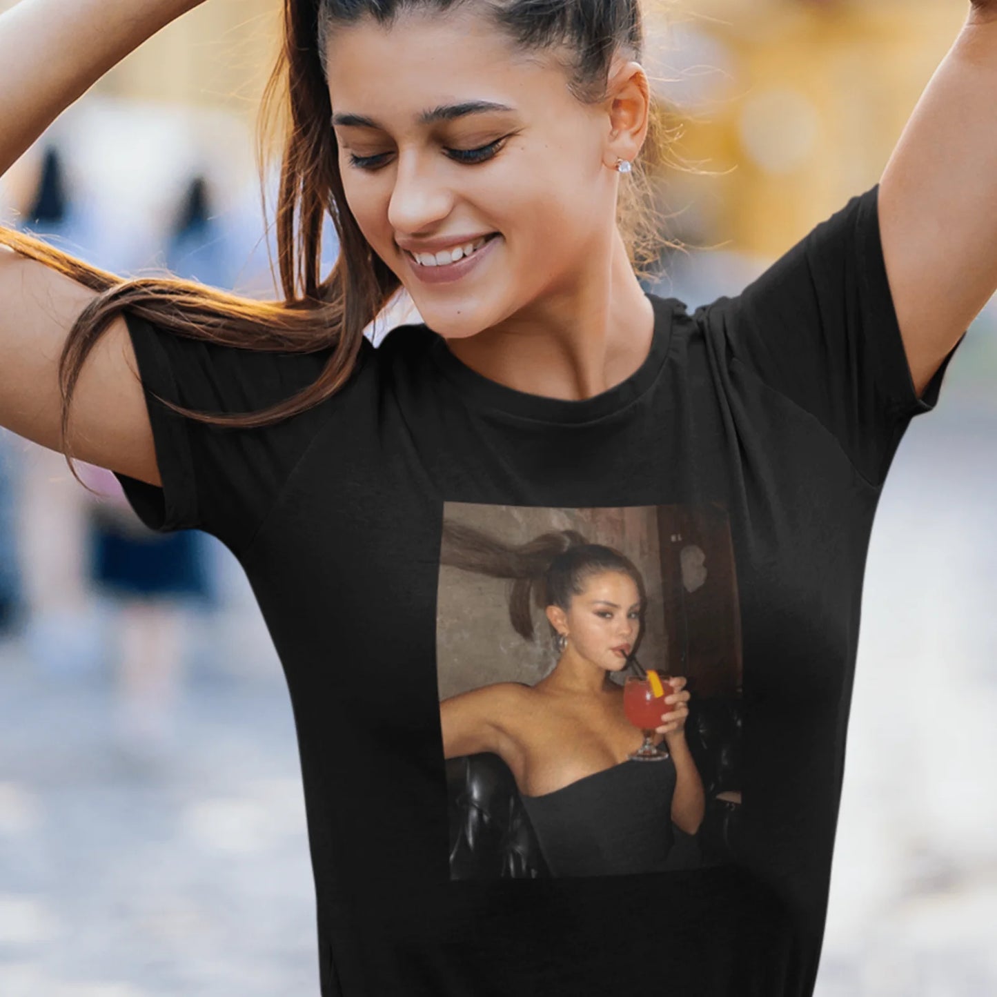 Holka v černém tričku se Selenou Gomez s drinkem v ruce
