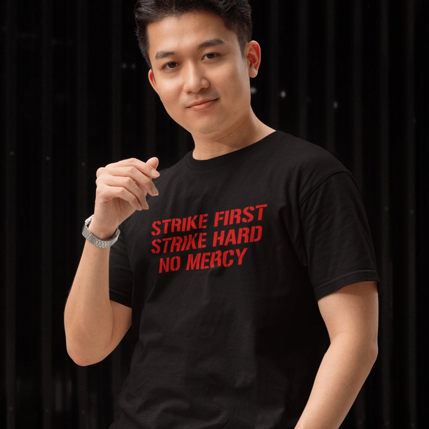 Kluk v černém tričku s červeným nápisem Strike First, Strike Hard, No Mercy