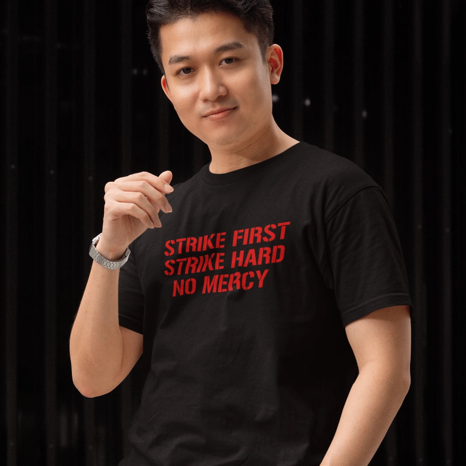 Kluk v černém tričku s červeným nápisem Strike First, Strike Hard, No Mercy