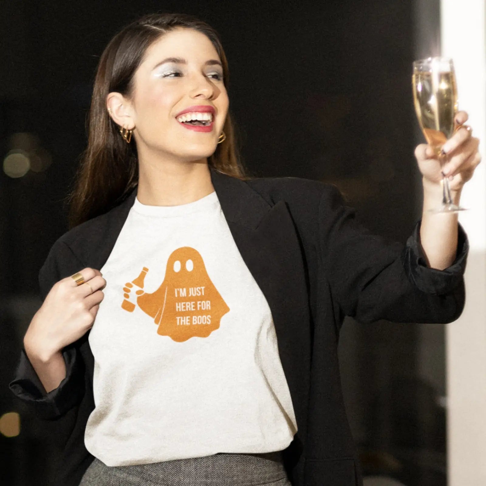 Mladá žena v saku a tričku s duchem a nápisem I’m just here for the boos