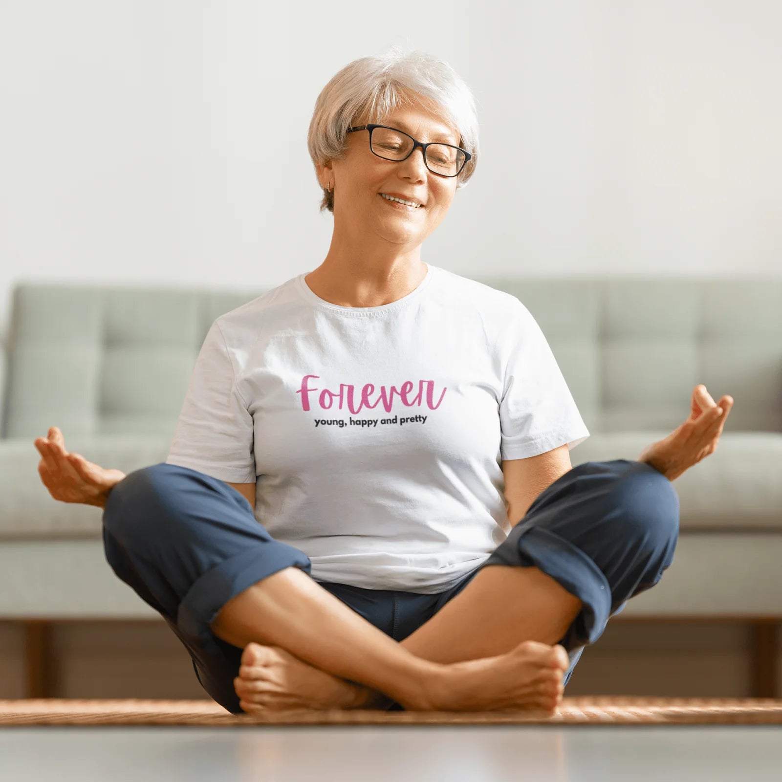 Meditující stará žena v bílém tričku s nápisem Forever Young, Happy & Pretty – věčně mladá a krásná!